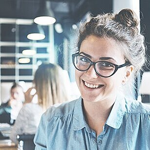 Porträt einer Studentin, die in einer Bibliothek sitzt