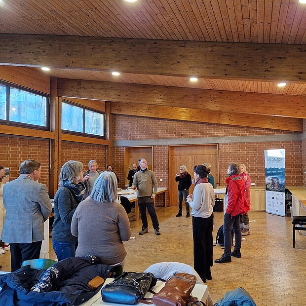 Ein Gruppe ist in einem Gemeinderaum versammelt und hört einen Vortrag.