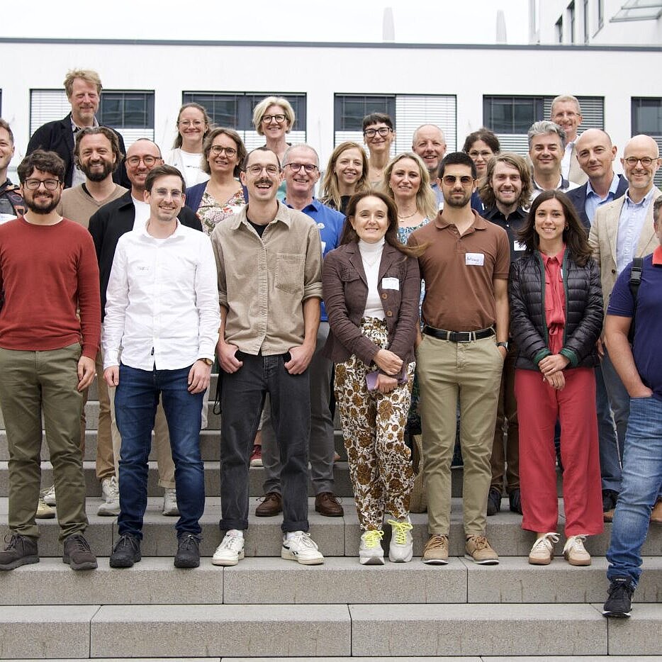 Gruppenfoto von über 20 Personen auf einer Betontreppe vor einem Bürogebäude.