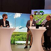 Auf der Bühne stehen die Referenten der Veranstaltung im Gespräch