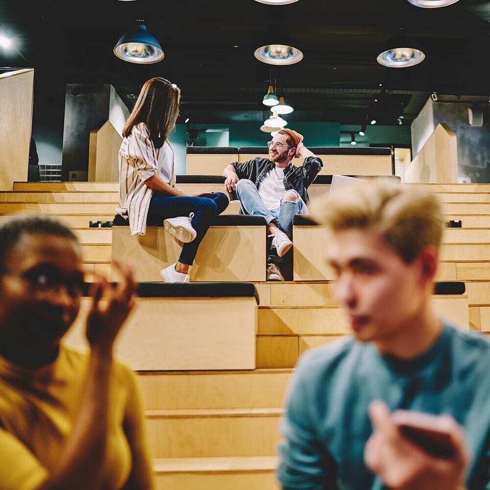 Junge Erwachsene sitzen auf den Stufen eines Vortragssaals