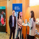 Bild zeigt drei Personen, die sich in einem professionellen oder konferenzähnlichen Umfeld unterhalten. 