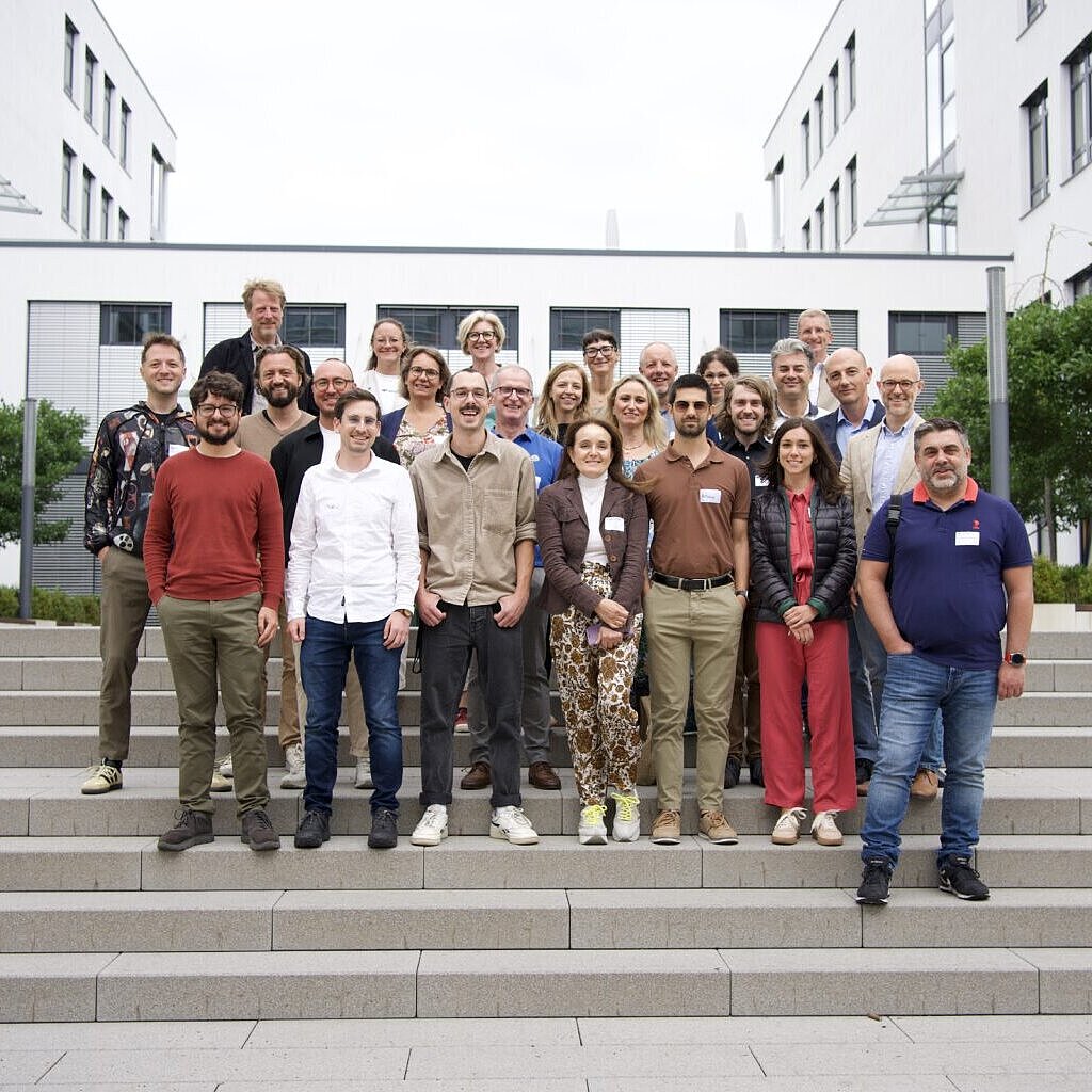 Gruppenfoto von über 20 Personen auf einer Betontreppe vor einem Bürogebäude.