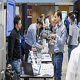 Zwei Männer im Gespräch an einem Ausstellungsstand.