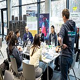 Mehrere Personen arbeiten an Laptops, während sie an einem Tisch zusammensitzen und Ideen austauschen.