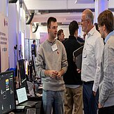 Benedikt Baier in front of the 6G-life booth, explaining the project on the Thinknet 6G Summit.