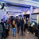 A look into one side of the Thinknet 6G Summit exhibition, showing the booths on the sides and people in the middle.