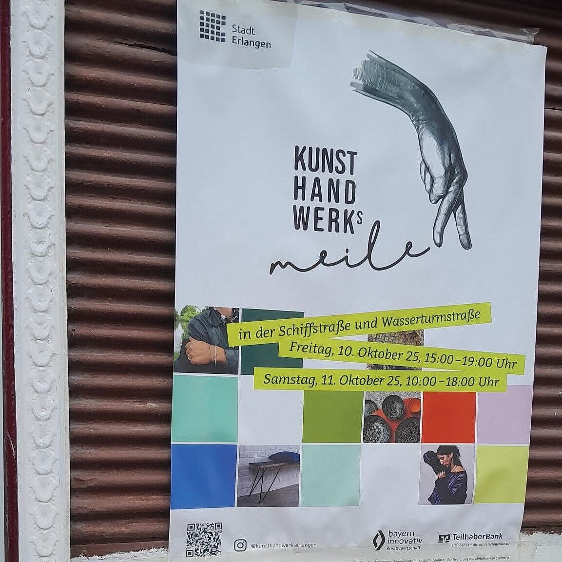 Poster der Kunsthandwerksmeile an einer Wand. 