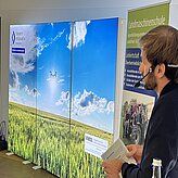 Hintergrundbild der Veranstaltung - grünes Feld mit blauem Himmel und einer fliegenden Drohne