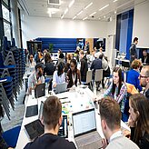 Menschen sitzen an Tischen und arbeiten an Laptops