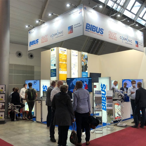 Menschen stehen vor einem Stand auf einer Messe