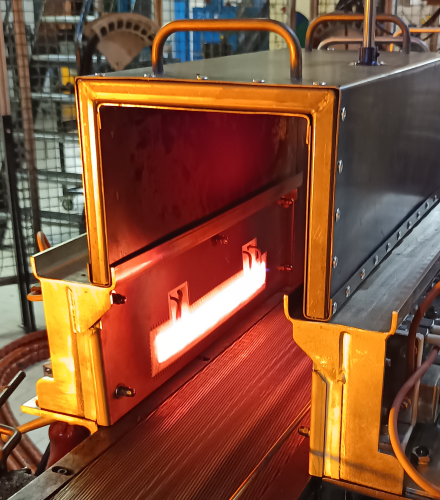 Geöffneter technischer Industrieofen mit sichtbarem Heizmodul und Transportband, das in den Ofen führt.